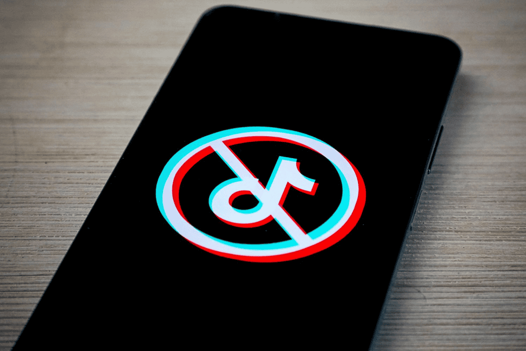 Smartphone displaying a banned TikTok logo, featuring a crossed-out icon on a red and blue circular background.